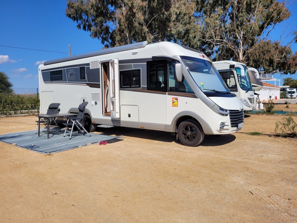 Husbil uppställd på camping i Europa med bord och stolar utanför, perfekt för vintercamping i Spanien