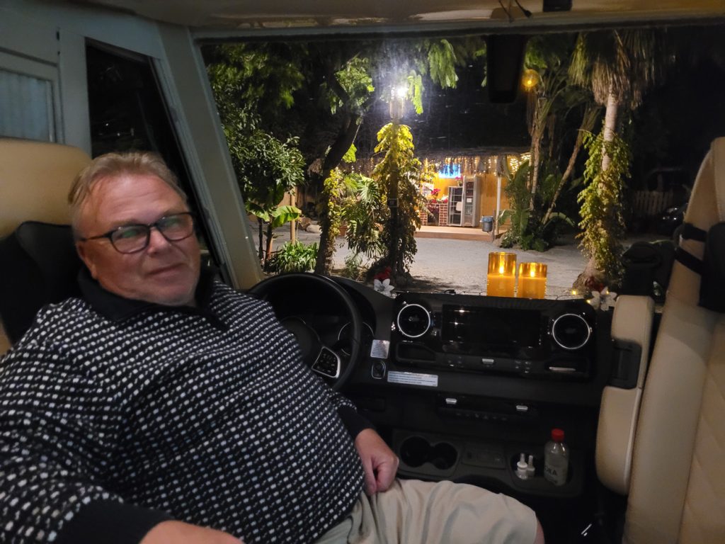 Avkoppling under camping i Europa – man njuter i husbil med utsikt över kvällsbelyst camping i Spanien