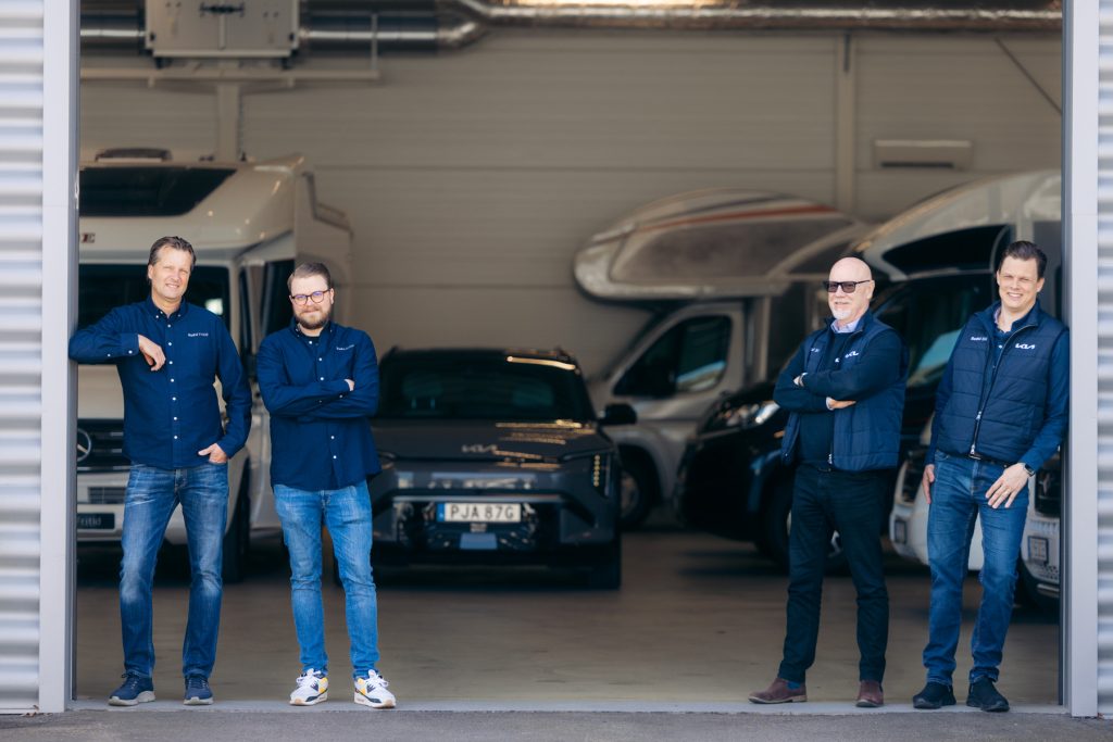 Personal från Rudvi framför husbilar och bilar i bilhallen – en del av det engagerade teamet hos Rudvi.