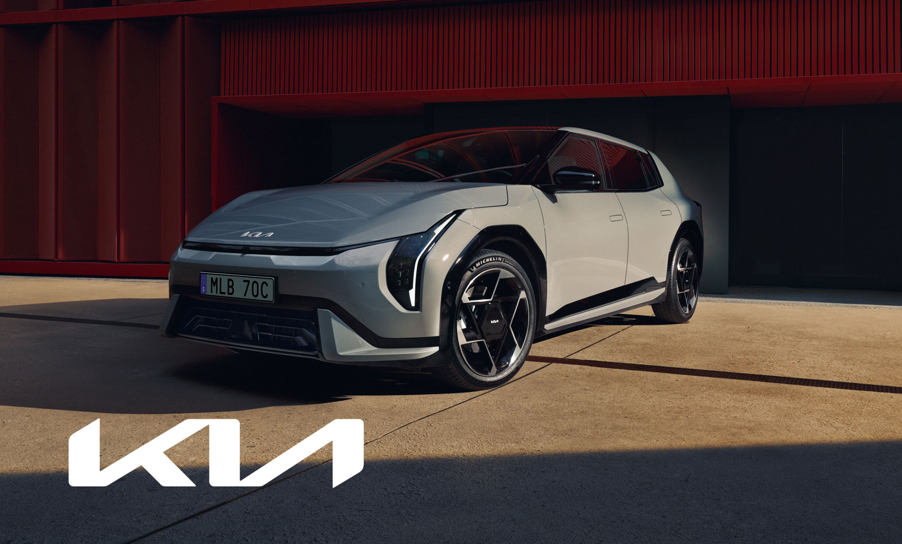 Kia EV4 fotograferad framför modern byggnad – med Kia-logotyp i fokus.